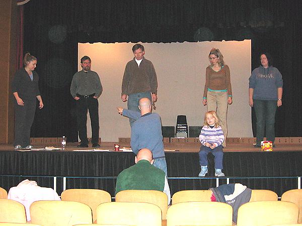 Brian points on stage from the pit while the cast listens