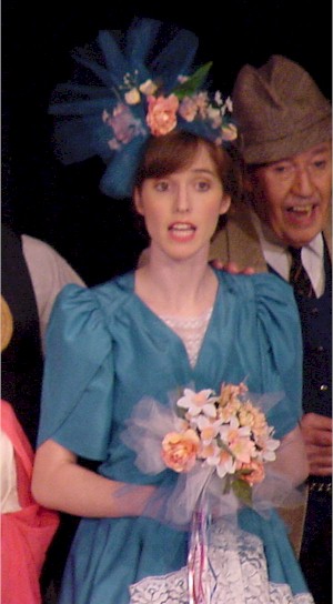 Susanne Farrow sings in a blue costume dress.